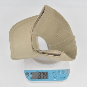 Detailed view of khaki baseball cap weight showing 87.4g on a digital scale