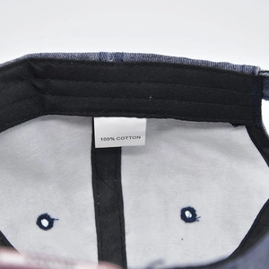 Detail view of denim baseball cap interior showing 100% cotton label and stitching