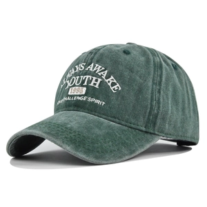 Détail d'une casquette vintage vert foncé avec broderie YOUTH et texture délavée usée
