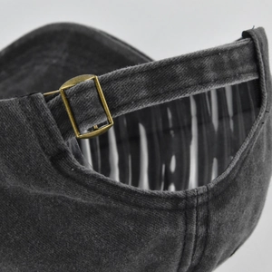 Détail de la boucle en bronze réglable sur la casquette en coton noir délavé vintage