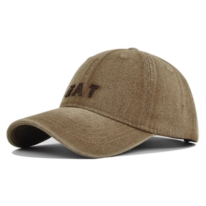 Detail of EAT embroidery on washed khaki denim baseball cap with vintage distressed texture