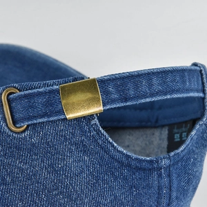 Macro view of adjustable metal buckle and stitching details on a washed denim baseball cap