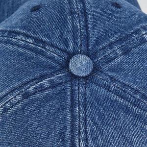 Close-up of blue washed denim baseball cap top with button and stitching details