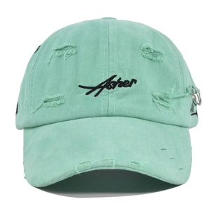 Detail view of mint green washed cotton cap with distressed holes and silver metal rings
