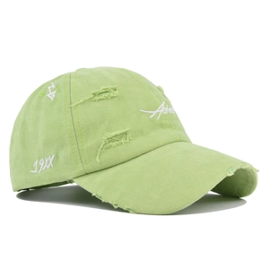Detail showing distressed holes and white embroidery on a light green baseball cap