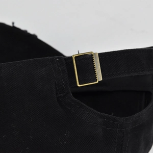 Detailed close-up of the vintage bronze buckle and adjustable strap on a black baseball cap
