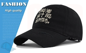 Close-up of distressed black cotton baseball cap with white cross embroidery and letter detail