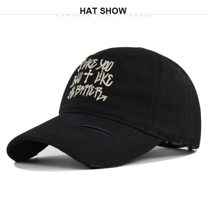 Close-up of cross embroidery and distressed detail on black cotton baseball cap