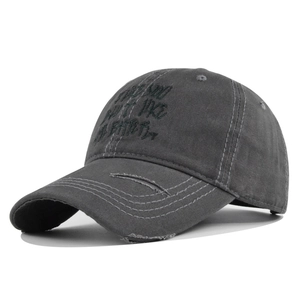 Detailed view of embroidery and distressed wash on a charcoal grey cotton baseball cap