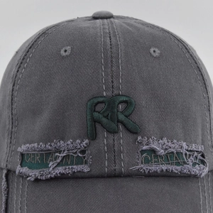 Detail of grey distressed baseball cap with RR embroidery and CERTAINTY fabric rips