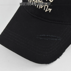Detailed close-up of cross embroidery and distressed brim on a black cotton baseball cap