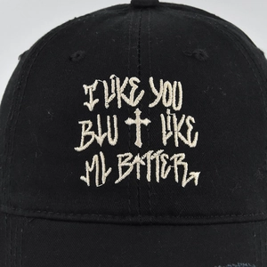 Detail of cross embroidery and quote on black cotton baseball cap for a street style look