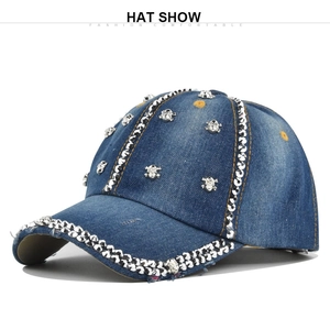 Détails rapprochés des rivets crâne et des strass sur la casquette en jean bleu