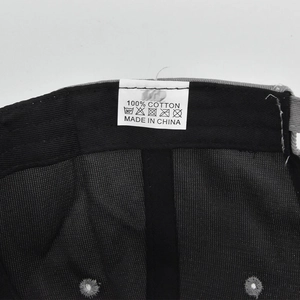 Detail view of the 100% cotton inner lining and wash label on a black baseball cap