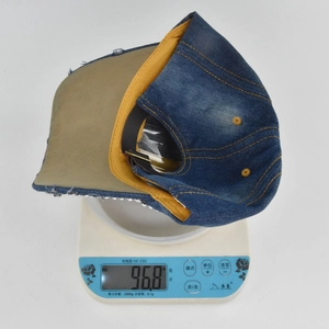 Détail de la casquette en denim avec strass argentés et boucle métallique réglable au dos