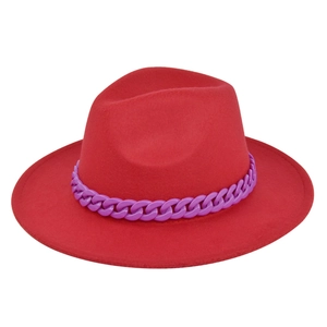 Dettaglio di cappello fedora rosso con catena decorativa viola su sfondo bianco