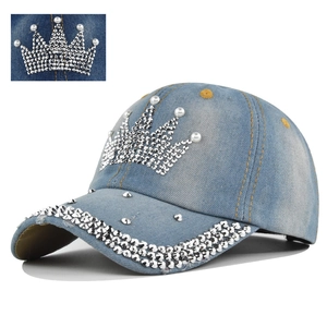 Close-up of rhinestone crown pattern and silver studs on light blue denim baseball cap