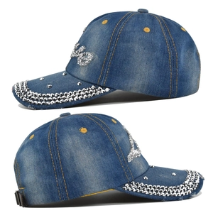 Detailed view of silver rhinestones and yellow stitching on washed blue denim baseball cap