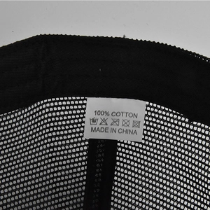 Detailed macro view of 100% cotton wash label on breathable black mesh baseball cap