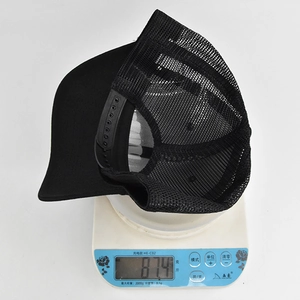 Close-up of a lightweight black mesh trucker hat weighing only 87.4g on a white scale