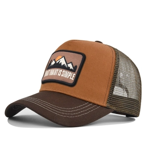 Detail of embroidered mountain patch on khaki mesh trucker hat with WHAT I WANT IS SIMPLE text