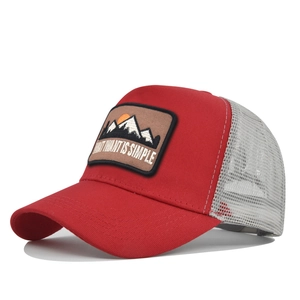Detail of red and grey trucker hat featuring a mountain patch and mesh back design