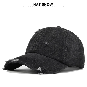 Close-up of distressed details and frayed holes on dark grey vintage washed denim cap