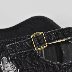 Close-up of vintage black denim baseball cap with bronze metal strap buckle and worn detail