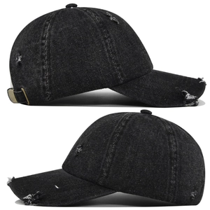 Detail of washed black denim baseball cap showing distressed holes and metal buckle strap