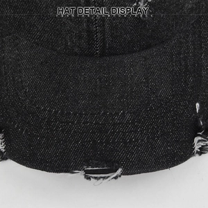 Detailed close-up showing distressed denim texture and stitching on the black baseball cap