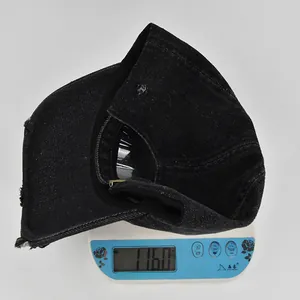 Detailed view showing a black distressed denim baseball cap weighing approximately 116 grams