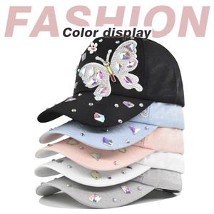 Detailed display of five colors of butterfly rhinestone baseball caps stacked on white background