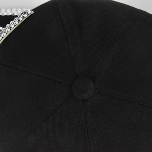 Detail van zwarte katoenen baseballpet met zilveren strass-steentjes en stiksel op de bovenkant
