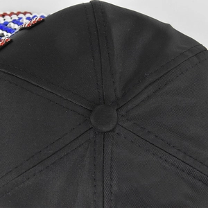 Detail van de bovenkant van de zwarte honkbalpet met stiksels en kleurrijke strass-accenten