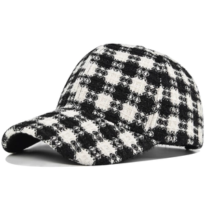 Close-up of thick black and cream plaid tweed texture on an autumn winter baseball cap