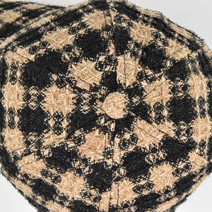 Macro shot of tweed baseball cap top featuring black and beige floral weave pattern