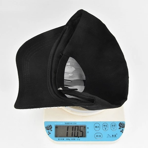 Gros plan d'une casquette de baseball en coton noir sur une balance pesant 110,5g net