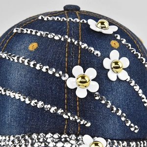 Close-up of denim baseball cap with silver rhinestones and white floral accents
