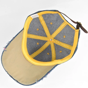 Detail of denim baseball cap interior with yellow sweatband and adjustable leather strap
