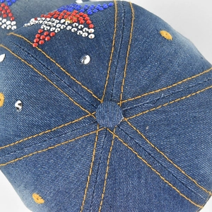 Detailed top view of blue denim baseball cap with rhinestone star and yellow stitching