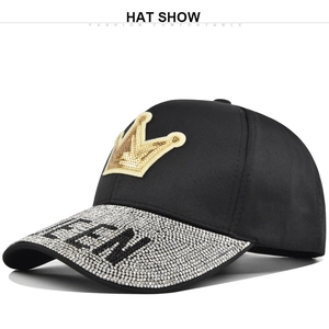 Detailed close-up of Queen rhinestone lettering and gold crown patch on black baseball cap