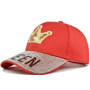 Red baseball cap with golden crown patch and silver rhinestone QUEEN lettering design