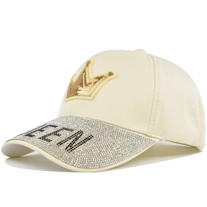 Detailed view of the sparkling rhinestone QUEEN logo and crown on the cream baseball cap
