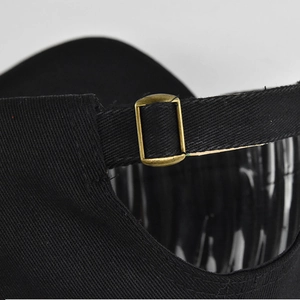 Détail de la boucle en métal bronze réglable et des coutures sur une casquette noire