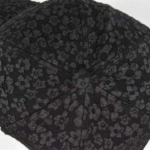 Detail of black baseball cap featuring textured floral patterns and a central top button