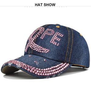 Détail de strass roses formant HOPE et ruban sur une casquette de baseball en jean bleu