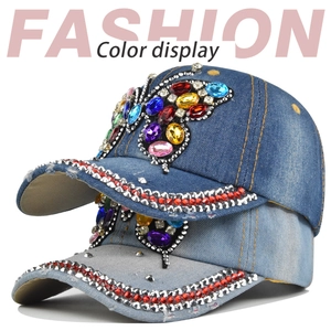 Dettaglio di cappelli da baseball in denim con farfalla di strass colorati e tesa decorata