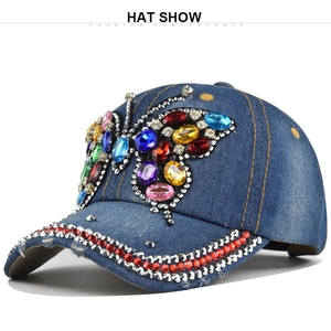 Dettaglio farfalla in strass colorati su cappellino da baseball in denim blu con cuciture gialle