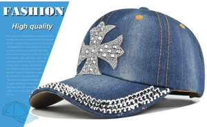Detail of blue denim baseball cap featuring rhinestone cross and studded brim accents