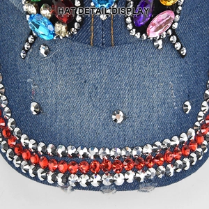 Dettaglio macro di strass colorati e gemme sulla corona del berretto in denim blu